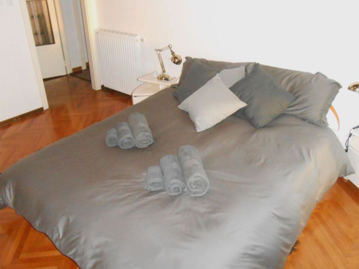 room with double king bed with pillows and cover, door in the background