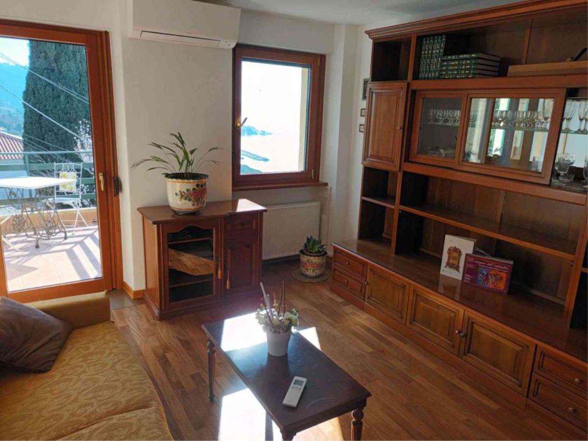 divano con tavolino, grande armadio a muro, mobiletto con vaso e fiori, finestra, porta a vetri, aria condizionata